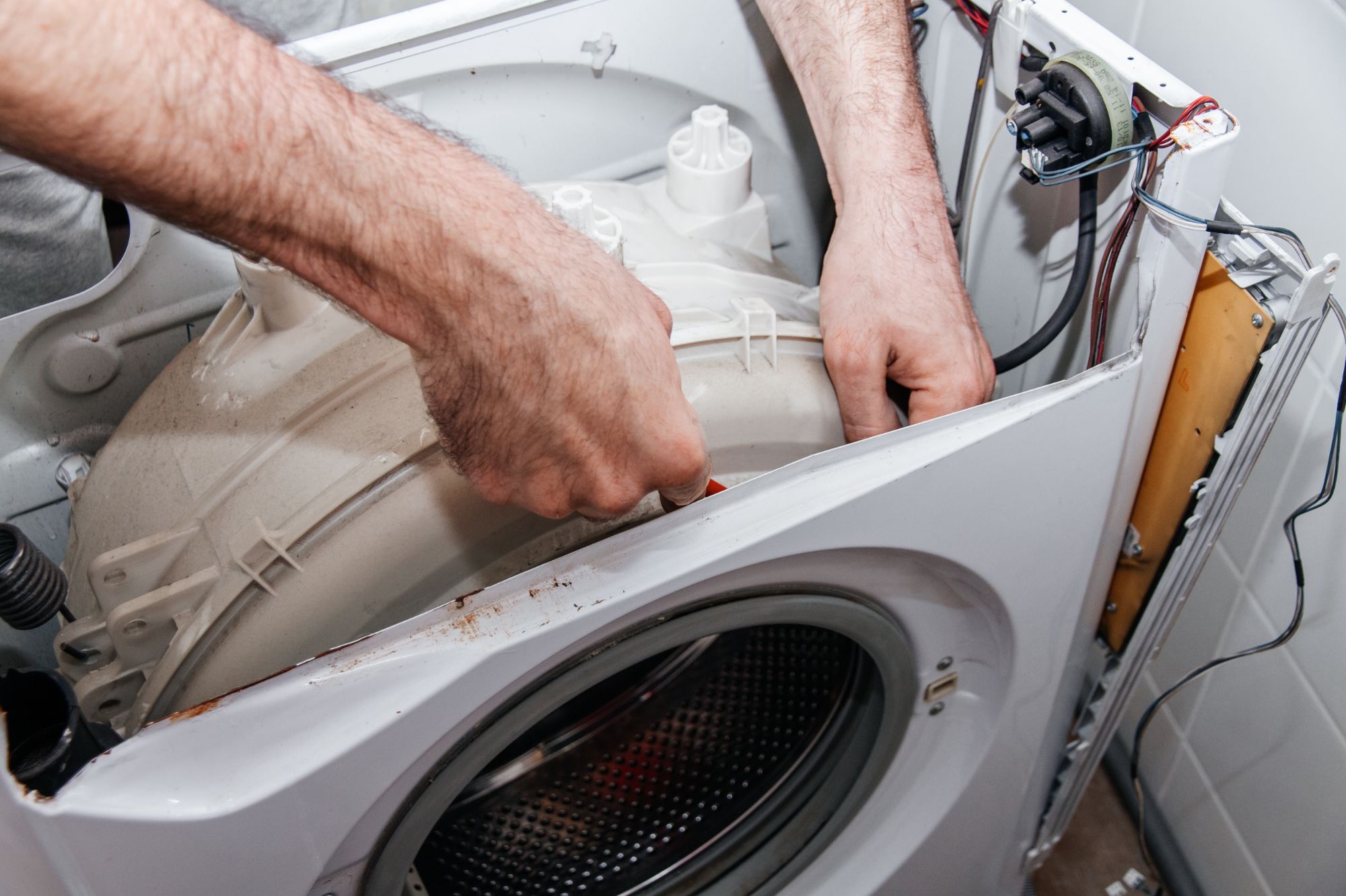 Technician removing motor component from washing machine during repair