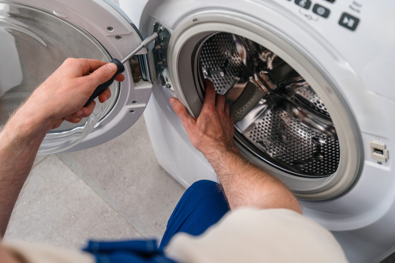 Man opening washing machine door with hand on handle